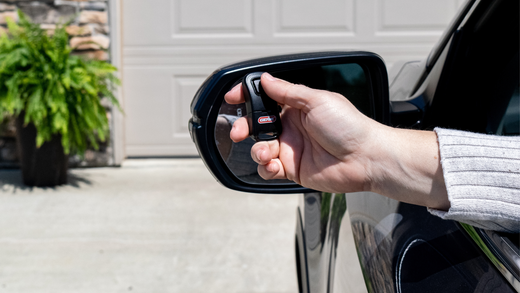 Hand holding a Genie garage door opener remote