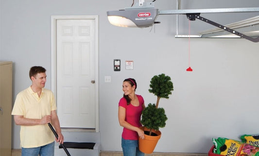 Two people working in a garage with a Genie garage door opener installed