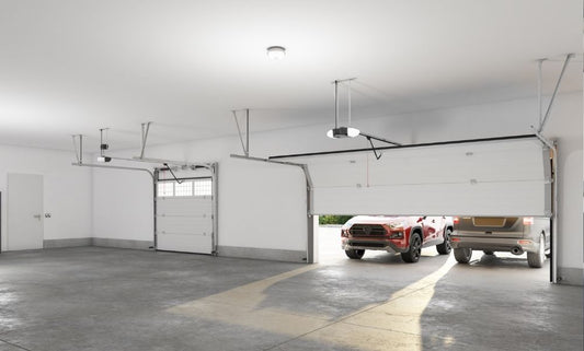 Empty garage with Genie garage door openers installed and two vehicles outside the door
