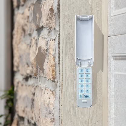 A white electronic keypad lock mounted on a light-colored wooden door next to a stone wall.