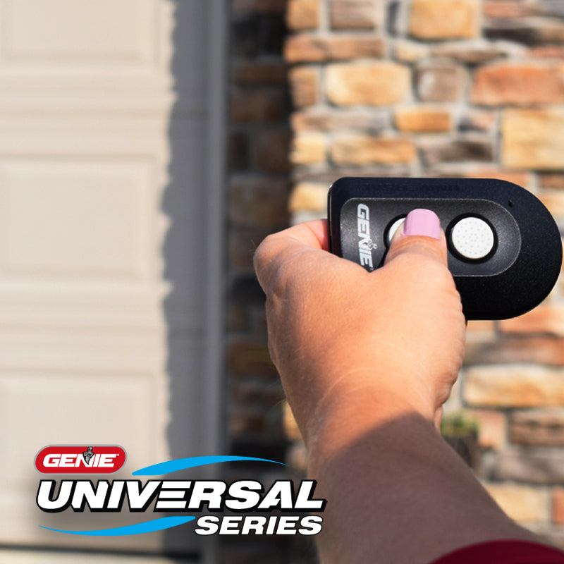 Genie two button universal garage door opener remote being used to open a garage door
