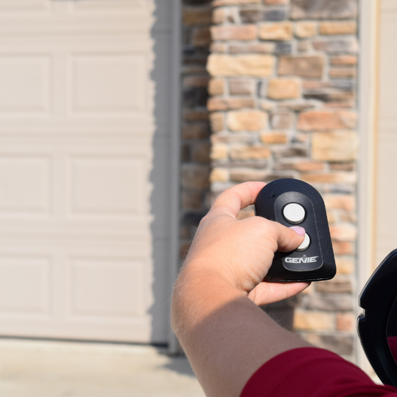 Person pressing the button on the 2 button Universal Garage Door Opener remote